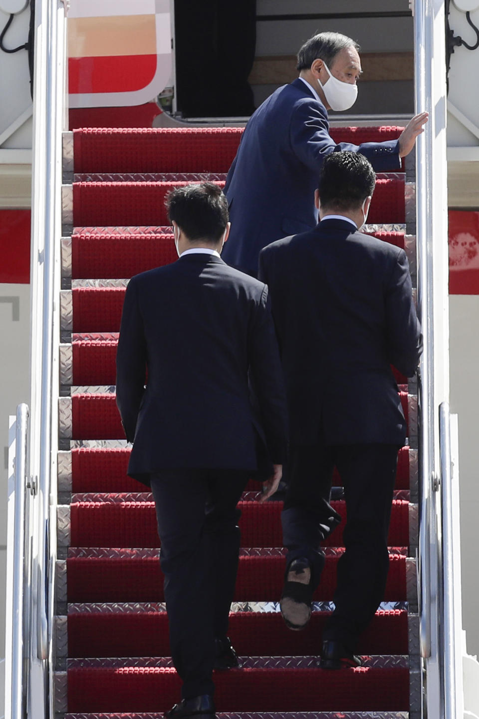 Japanese Prime Minister Yoshihide Suga, top, waves as he boards his plane to depart at Andrews Air Force Base, Md., Saturday, April 17, 2021, after his visit to Washington. (AP Photo/Luis M. Alvarez)