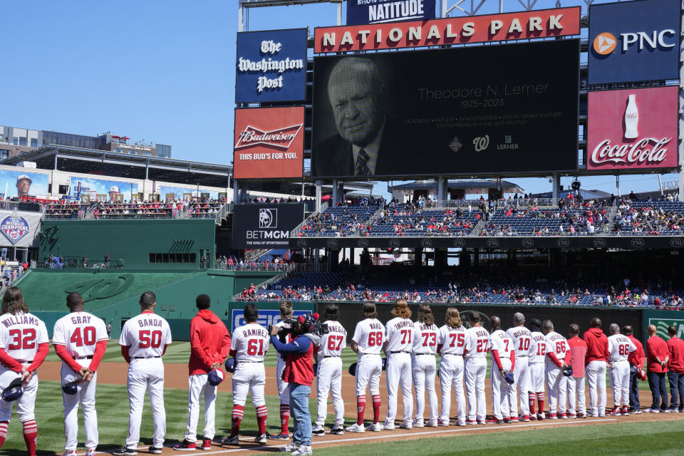 Members of the Washington Nationals stand on the field as a video memorializing Theodore Lerner, Managing Principal Owner of the Nationals, is broadcast before an opening day baseball game between the Nationals and the Atlanta Braves at Nationals Park, Thursday, March 30, 2023, in Washington. (AP Photo/Alex Brandon)