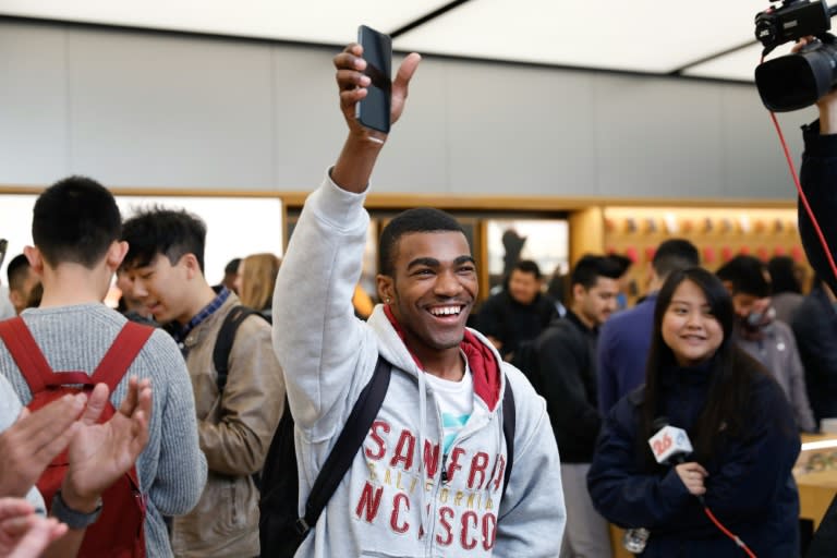 A customer holds up an iPhone X and smiles after purchasing it on launch day at the Apple Store Union Square on the launch day for the new flagship smartphone