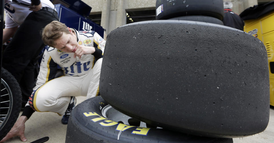 Brad Keselowski examines wear on tires he used during a practice session for the NASCAR Sprint Cup Series auto race at Texas Motor Speedway in Fort Worth, Texas, Saturday, April 5, 2014. (AP Photo/LM Otero)