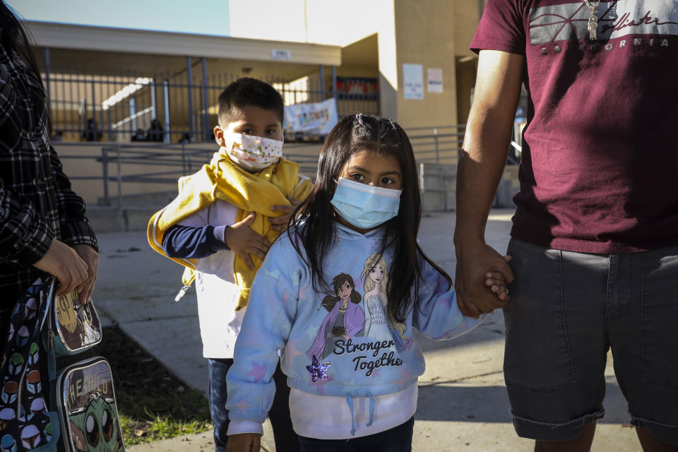  Jose Martinez and his sister Julissa stand with their mother Laura Gomez and father Felipe Martinez outside the John G. Whittier School in Long Beach, Calif., as school returns after winter break and a spike in positive COVID-19 cases.
