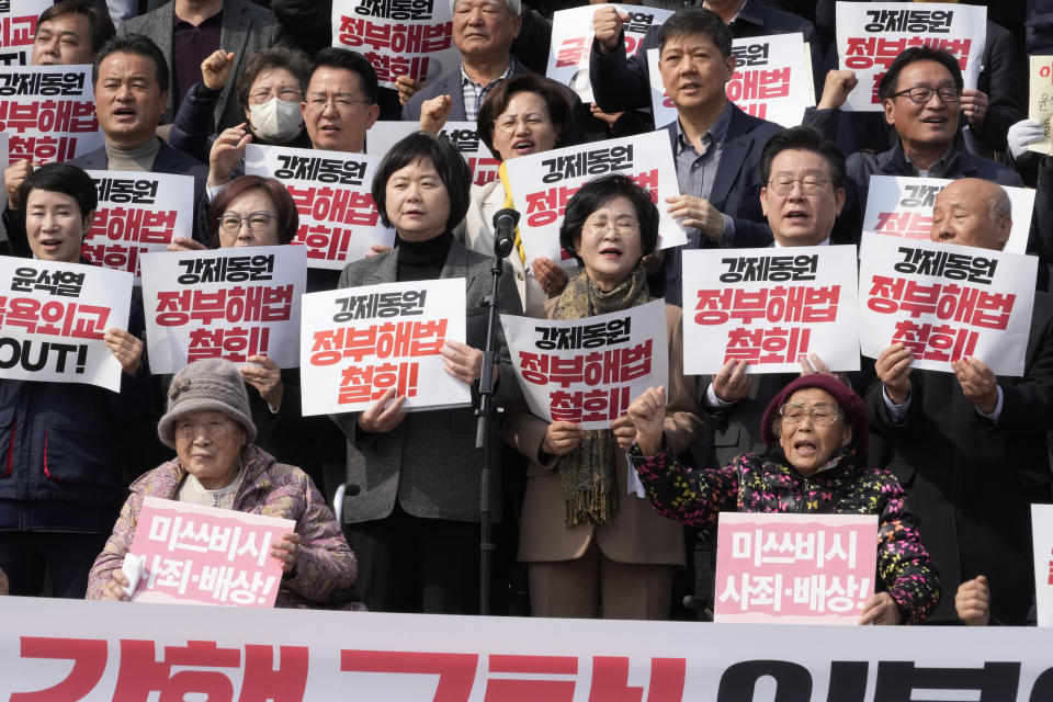 South Korean forced labor victims Yang Geum-deok, bottom right, and Kim Seong-ju, bottom left, participate in a rally against the South Korean government's announcement of a plan over the issue of compensation for forced labors at the National Assembly in Seoul, South Korea, Tuesday, March 7, 2023. South Korean President Yoon Suk Yeol on Tuesday defended his government's contentious plan to use local funds to compensate Koreans enslaved by Japanese companies before the end of World War II, saying it's crucial for Seoul to build future-oriented ties with its former colonial overlord. The signs read "Withdraw, the government's announcement of a plan over the issue of compensation for forced labors." (AP Photo/Ahn Young-joon)