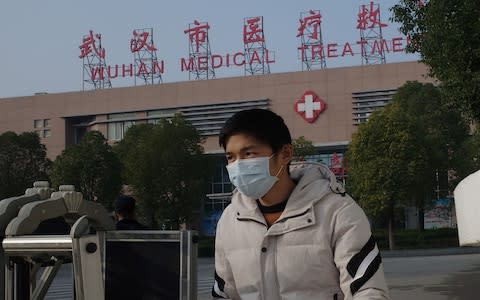 A man leaves the Wuhan Medical Treatment Centre, where a man who died from a respiratory illness was confined - Credit: &nbsp;NOEL CELIS/AFP/Getty