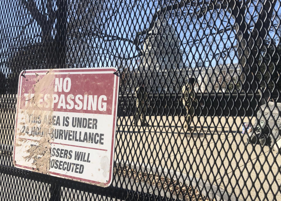 Members of the National Guard stand inside anti-scaling fencing that surrounds the Capitol complex, Sunday, Jan. 10, 2021, in Washington. (AP Photo/Alan Fram)