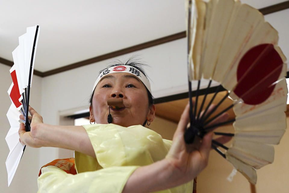 Olympic fan Kyoko Ishikawa shows her cheering at her home Saturday, April 10, 2021, in Tokyo. Ishikawa, president of an IT company, has attended every Summer Olympics since Barcelona in 1992, becoming famous as an unofficial "International Olympic Cheerleader." She relishes joining in with fans from everywhere to cheer for their athletes. (AP Photo/Eugene Hoshiko)