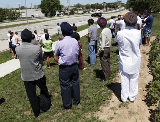 Bystanders look on as SWAT officers surround the Sikh Temple of Wisconsin where a gunman attacked worshippers on Sunday killing at least six people before he was himself shot dead by police