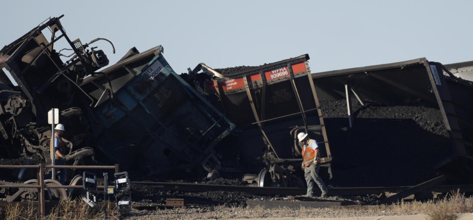 FILE - A worker walks by derailed cars that toppled and collapsed a bridge over Interstate 25 northbound, Monday, Oct. 16, 2023, north of Pueblo, Colo. The major freight railroads all promised safety improvements after the fiery derailment in eastern Ohio one year ago, but they have yet to make a meaningful improvement in the safety statistics and efforts to reform the industry have stalled in Congress. (AP Photo/David Zalubowski, File)