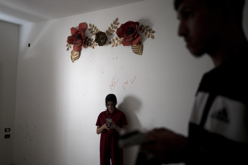 Rahaf, the younger sister of Mohammed Zalabani, a 13 year-old Palestinian in juvenile detention, awaiting trial on murder charges for a Feb. 13 stabbing attack, scrolls through her mother's phone for pictures of her brother in the family's emptied apartment which is slated to be demolished by Israeli authorities in Shuafat refugee camp in east Jerusalem, Wednesday, Aug. 30, 2023. An Israeli court last week dismissed the family's appeal and decided to destroy their home of nearly three years in Shuafat refugee camp, a crowded and garbage-strewn district of east Jerusalem, as further punishment. The demolition could occur anytime in the coming days. (AP Photo/Maya Alleruzzo)