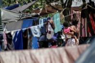 Asylum-seeking migrants, who were apprehended and returned to Mexico under Title 42 for crossing the border from Mexico into the U.S., are seen in a public square where hundreds of migrants live in tents, in Reynosa