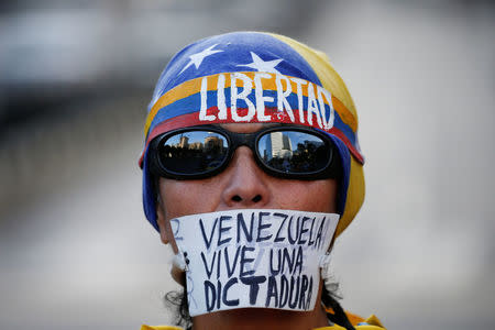 An opposition supporter with a sign that reads, "Venezuela lives a dictatorship", take part in a protest against Venezuelan President Nicolas Maduro's government in Caracas, Venezuela March 31, 2017. REUTERS/Carlos Garcia Rawlins