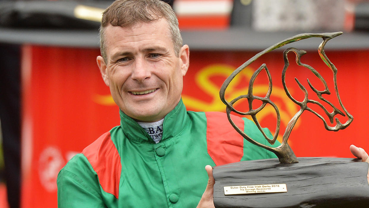 Jockey Pat Smullen is pictured lifting a trophy.