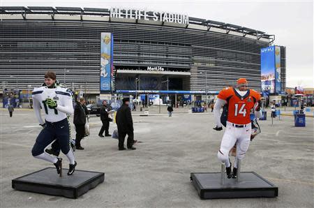 Fans pose behind Seattle Seahwawks and Denver Broncos mannequins outside the stadium before the start of the NFL Super Bowl XLVIII football game in East Rutherford, New Jersey, February 2, 2014. REUTERS/Shannon Stapleton