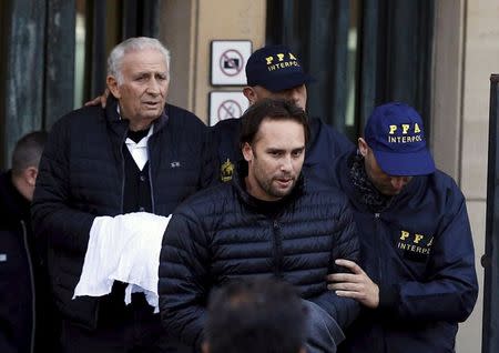 Argentine businessmen Mariano Jinkis (C) and his father Hugo (L, back) who are wanted by U.S. prosecutors in a FIFA bribery investigation, are escorted by police officers after they turned themselves in on to authorities in Buenos Aires, Argentina, June 18, 2015. REUTERS/Enrique Marcarian