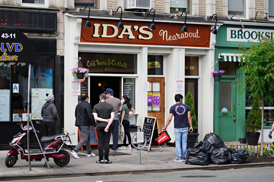 NEW YORK, NEW YORK - MAY 25: People wearing protective masks stand outside a restaurant serving to-go food and drinks in Sunnyside during the coronavirus pandemic on May 25, 2020 in the Queens Borough of New York City. Government guidelines encourage wearing a mask in public with strong social distancing in effect as all 50 states in the USA have begun a gradual process to slowly reopen after weeks of stay-at-home measures to slow the spread of COVID-19. (Photo by Cindy Ord/Getty Images)