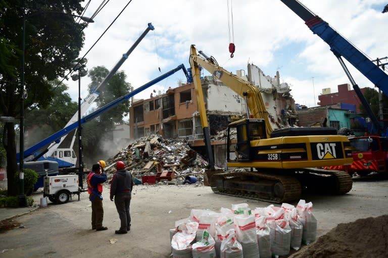 Technicians watch as a building seriously damaged by the September 19 earthquake is demolished in Mexico City on October 17, 2017