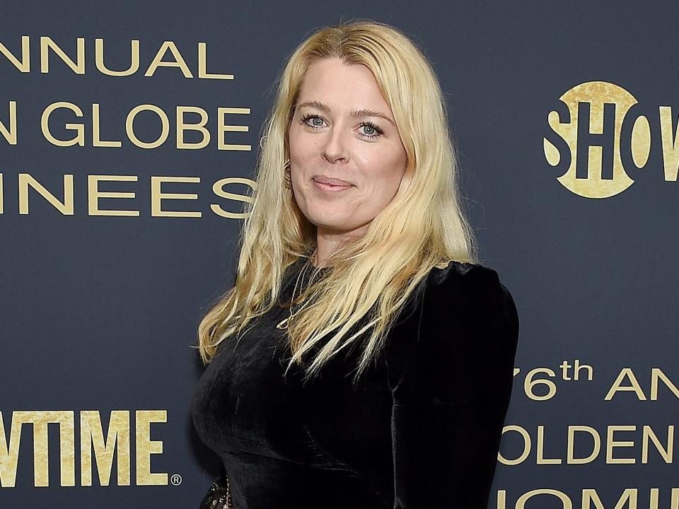 Amanda smiling in a black dress in front of a backdrop.