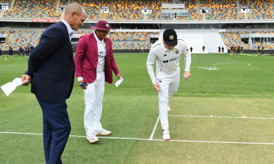 Queensland captain Usman Khawaja (second left) and his Western Australia counterpart Shaun Marsh eagerly check in on the outcome of the toss in their recent Sheffield Shield game.