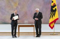 New elected German Chancellor Olaf Scholz, left, holds his letter of appointment presented by German President Frank-Walter Steinmeier, right, during a reception at Bellevue Palace in Berlin, Germany, Wednesday, Dec. 8, 2021. Scholz has become Germany's ninth post-World War II chancellor, opening a new era for the European Union’s most populous nation and largest economy after Angela Merkel’s 16-year tenure. Scholz’s government takes office with high hopes of modernizing. (Bernd Von Jutrczenka/dpa via AP)