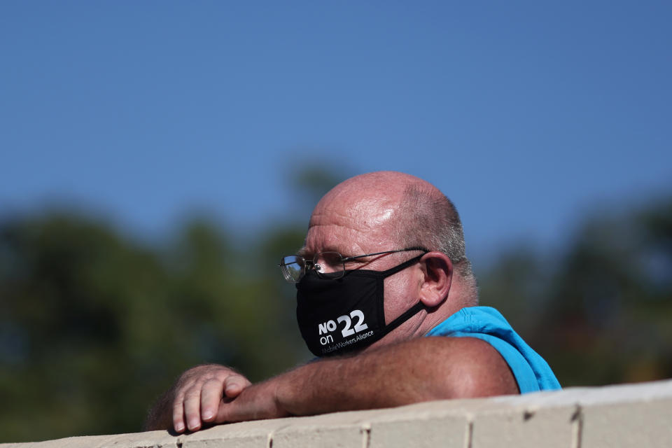 A man wears a protest mask as he watches a protest by Uber and Lyft rideshare drivers against California Proposition 22 that would classify app-based drivers as independent contractors and not employees or agents, during the coronavirus disease (COVID-19) outbreak, in Los Angeles, California, U.S., October 14, 2020. REUTERS/Lucy Nicholson