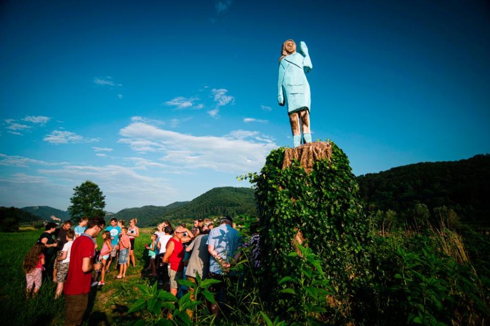 People gather around what conceptual artist Ales 'Maxi' Zupevc claims is the first ever monument of Melania Trump, set in the fields near the town of Sevnica, US First Lady's hometown, during a small inauguration celebration on July 5, 2019. | JURE MAKOVEC—AFP/Getty Images