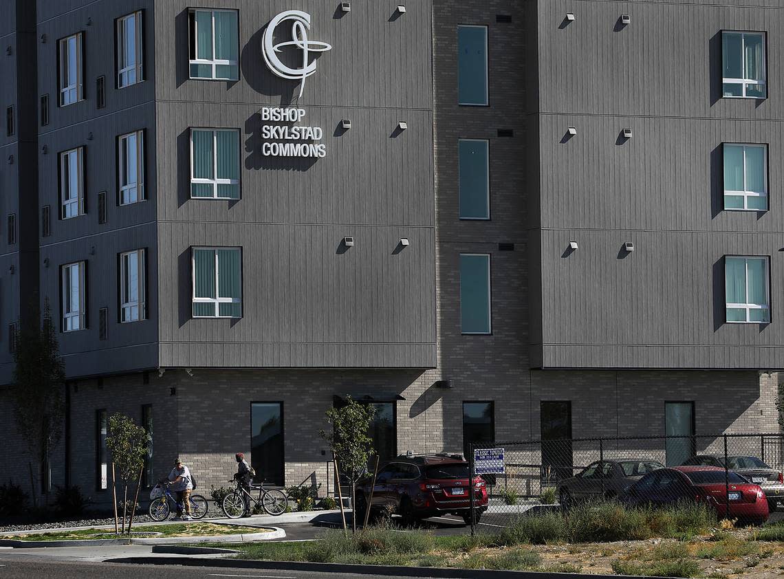 Two people with bicycles prepare to pedal away from the Bishop Skylstad Commons housing facility in Pasco. The recently built apartment style complex is a resource for the homeless.