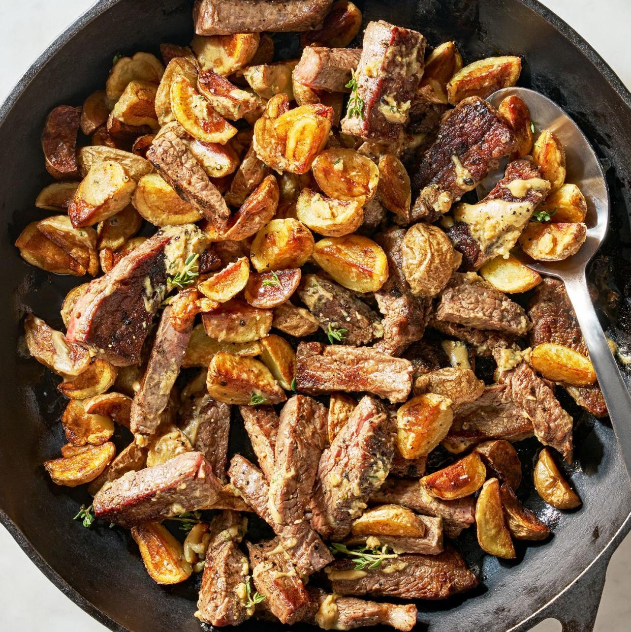 a skillet of crispy potatoes and tender, seared flank steak bathed in a tangy, savory garlic mustard butter sauce