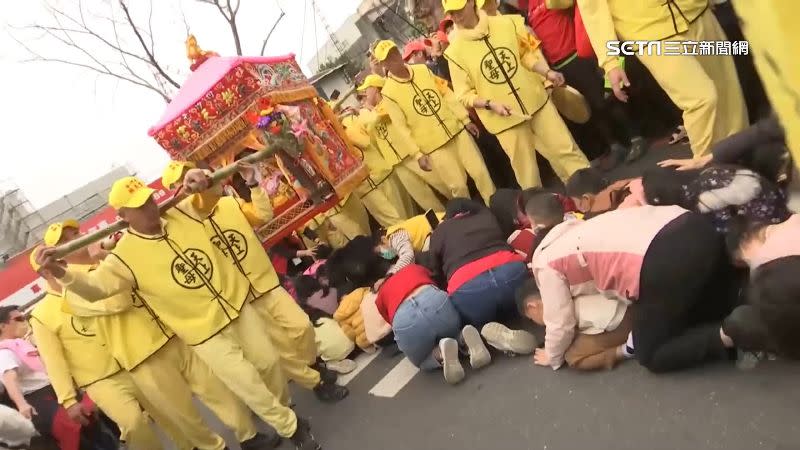 國小學生們跪在地上「鑽轎底」，希望獲得媽祖保佑。