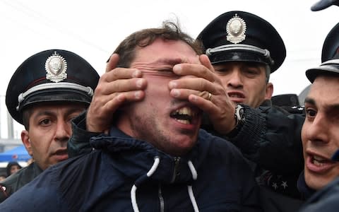 A policeman holds the face of a demonstrator   - Credit: REUTERS/Vahram Baghdasaryan/Photolure