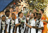 Juventus' Paulo Dybala, center left, and Juventus' Miralem Pjanic raise the trophy at the end of the Italian Super Cup final soccer match between AC Milan and Juventus at King Abdullah stadium in Jiddah, Saudi Arabia, Wednesday, Jan. 16, 2019. (AP Photo)