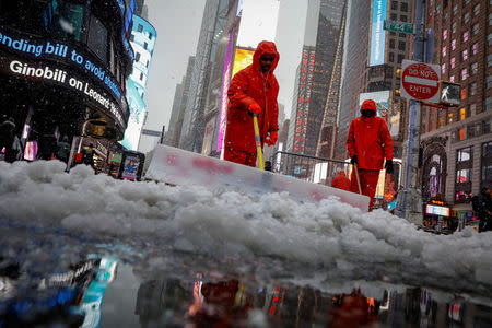 Workers clear snow during a winter nor'easter storm in Times Square in New York City, U.S., March 21, 2018. REUTERS/Brendan McDermid