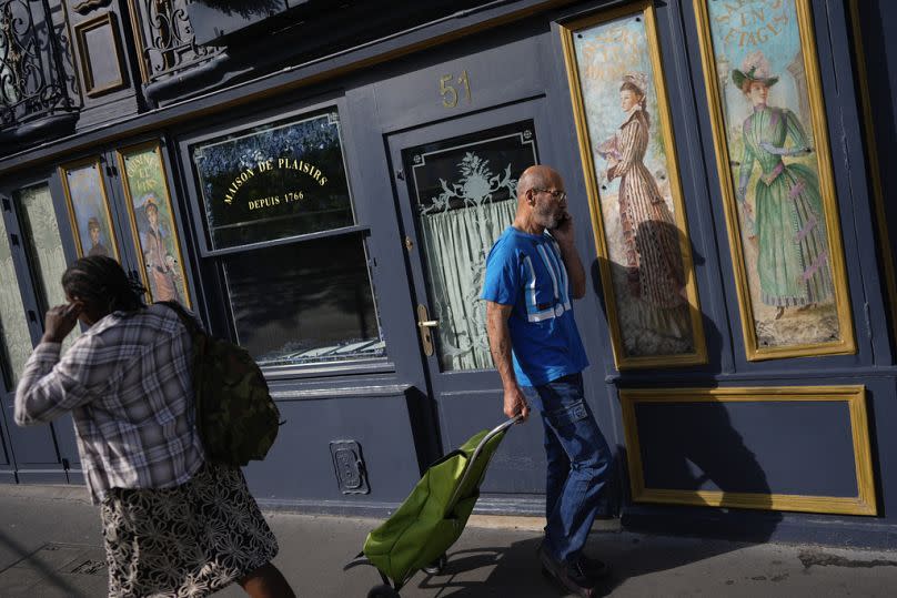 Un grupo de personas pasa por delante de un restaurante decorado con obras de arte, antes de los Juegos Olímpicos de Verano de 2024 en París, julio de 2024