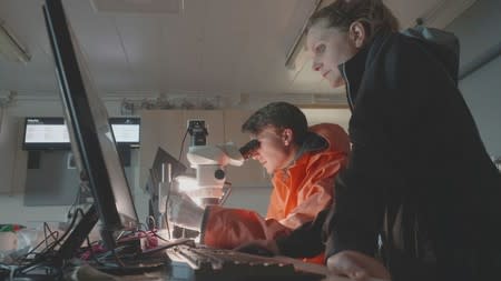 Scientists from the U.S.-led Northwest Passage Project inspect visuals of microplastics that were found in ice cores during an 18-day icebreaker expedition that took place in July and August 2019