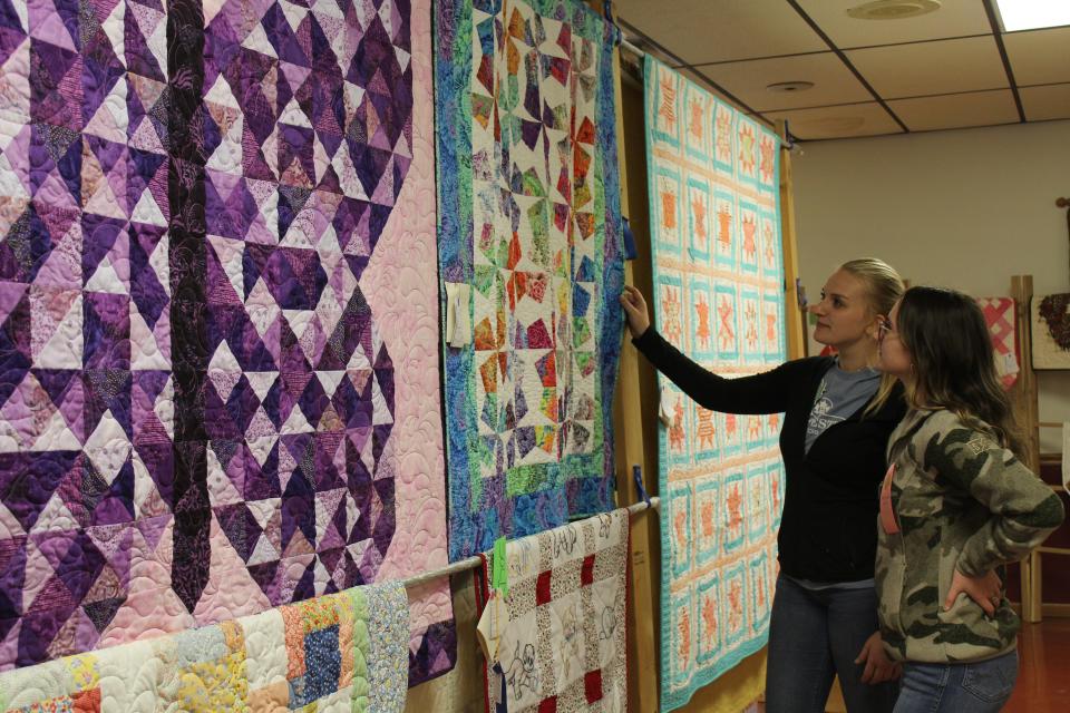 Grace Oakes and Maddy Faner stand by some of the displays at the Pennsylvania Maple Festival's annual Quilt Show at the firehall this past Saturday.