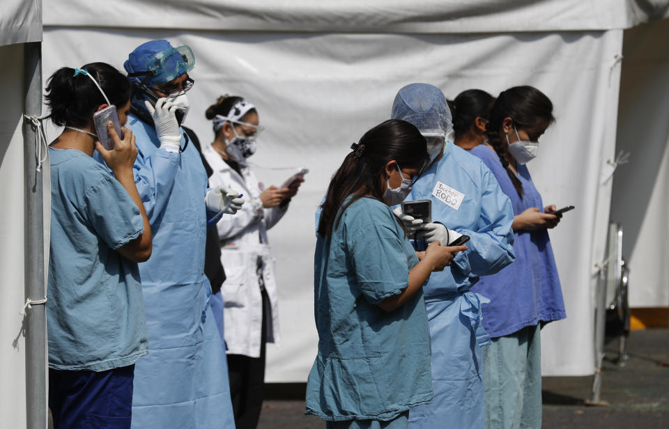 Health workers check their cell phones after an earthquake, outside the Juarez de Mexico public hospital in Mexico City, Tuesday, June 23, 2020. The earthquake centered near the resort of Huatulco in southern Mexico swayed buildings Tuesday in Mexico City and sent thousands into the streets. (AP Photo/Eduardo Verdugo)