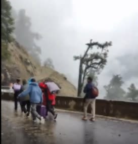 雲南省的獨龍江公路在當地時間 2 日因降雨導致發生山體滑坡事故，受困的遊客棄車拉行李走在馬路上。   圖 : 翻攝自騰訊網