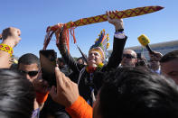 FILE - Brazilian President Jair Bolsonaro raises a "borduna," a traditional Indigenous weapon, outside Planalto presidential palace after receiving it as a gift from Indigenous people from various regions who support agro-business activities on Indigenous lands, in Brasilia, Brazil, Aug. 12, 2021. Bolsonaro has said that Indigenous people should be entitled to self-determination -- not just regarding possible mining, but all activities. (AP Photo/Eraldo Peres, File)