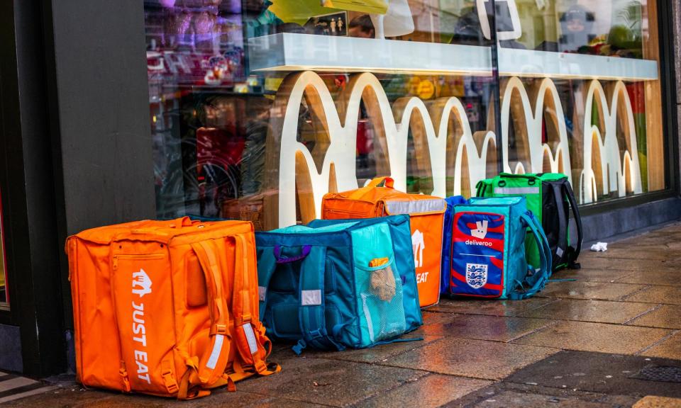 <span>Just Eat, Deliveroo and other delivery rider bags outside a McDonald’s in Ilford.</span><span>Photograph: Jill Mead/the Guardian</span>