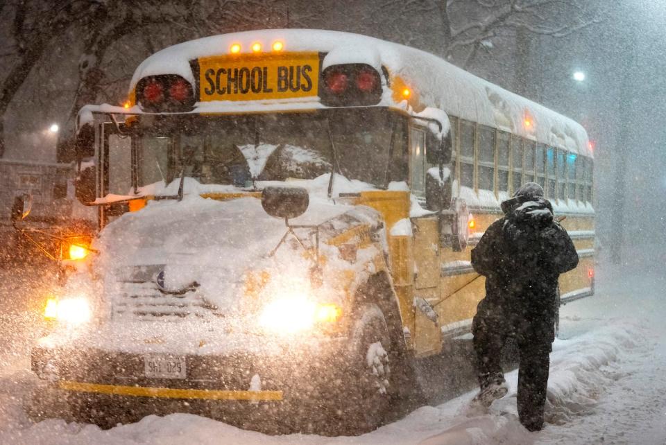 A school bus driver tries to clear snow as a winter storm causes the closure of schools in Toronto on Jan. 17, 2022.