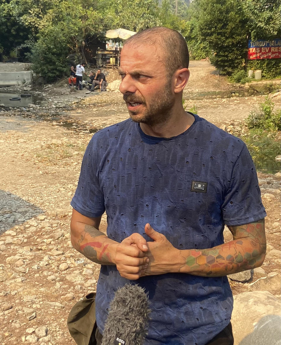 Turkish actor Tevfik Erman Kutlu speaks during an interview with The Associated Pressin Turgut village, near tourist resort of Marmaris, Mugla, Turkey, Wednesday, Aug. 4, 2021. Hundreds of volunteers have joined efforts to contain blazes that have swept through forests in Turkey's southern and southwestern coasts, fueled by a summer heatwave, low humidity and strong winds. The fires, described as Turkey's worst in living memory, have so far killed eight people _ including a teenaged volunteer who was carrying drinking water and other refreshments to firefighters in Marmaris. (AP Photo/Emre Tazegul)