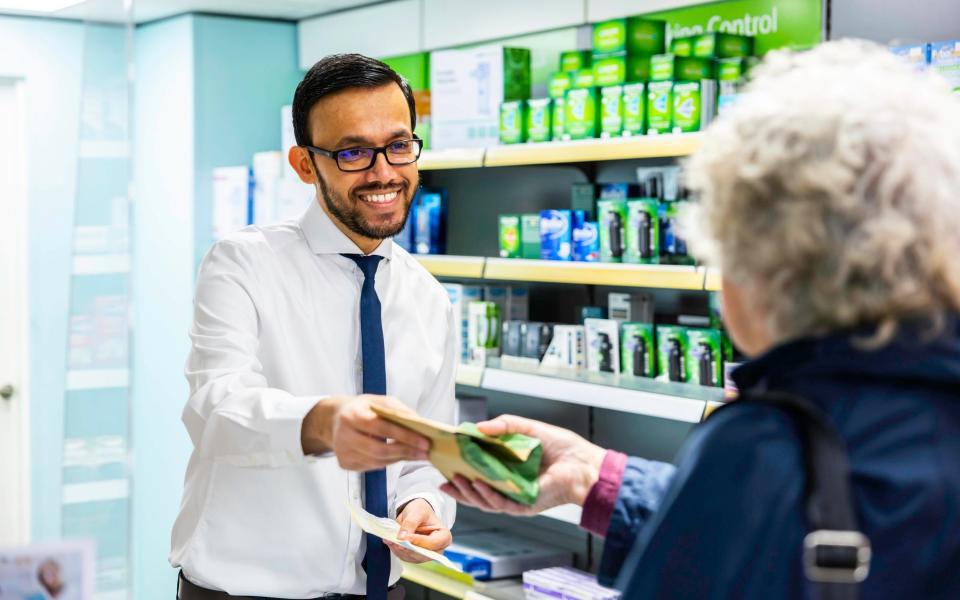 A pharmacist handing over prescribed medicine to a patient