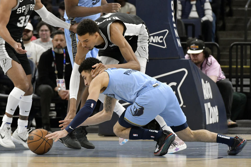 Memphis Grizzlies guard Scotty Pippen Jr., bottom, and San Antonio Spurs center Victor Wembanyama, top, reach for a loose ball in the first half of an NBA basketball game Tuesday, April 9, 2024, in Memphis, Tenn. (AP Photo/Brandon Dill)