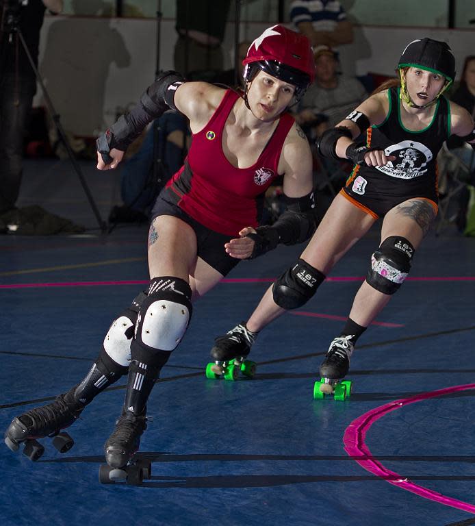 "Jammers" race each other for points during a clash between the DC Roller Girls (red) and the Rocktown Rollers, April 5, 2014, at the women's flat track Roller Derby at the Dulles Sportsplex in Sterling, Virginia