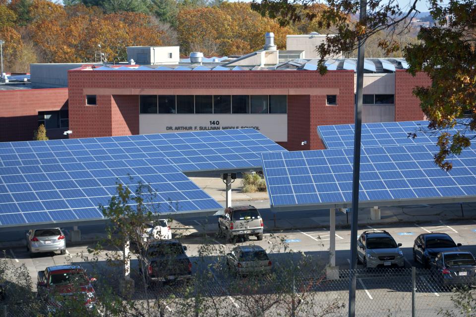 Solar panels are visible on the top of a carport in the parking lot of the Dr. Arthur F. Sullivan Middle School in Worcester.