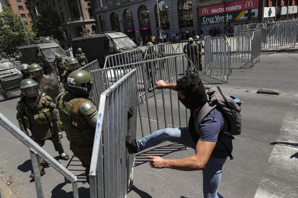 Un manifestante antigubernamental patea una barricada policial cerca del palacio presidencial de La Moneda en Santiago, Chile, el martes 12 de noviembre de 2019. (AP Foto / Esteban Felix)