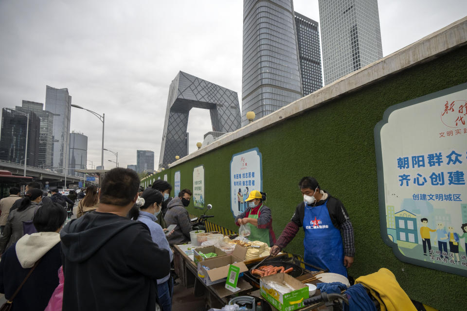 Street vendors wearing face masks make takeaway food for commuters at a cart in the central business district in Beijing, Friday, Oct. 28, 2022. (AP Photo/Mark Schiefelbein)