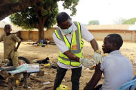 Yunusa Bawa, a community health worker, injects a man with AstraZeneca coronavirus vaccine in Sabon Kuje on the outskirts of Abuja, Nigeria, Monday, Dec 6, 2021. As Nigeria tries to meet an ambitious goal of fully vaccinating 55 million of its 206 million people in the next two months, health care workers in some parts of the country risk their lives to reach the rural population. (AP Photo/Gbemiga Olamikan)