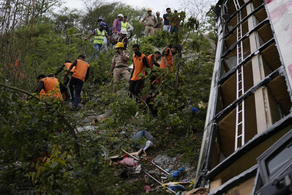 Jammu & Kashmir State Disaster Response Force (SDRF) personnel inspect the wreckage after a bus carrying Hindu pilgrims to a shrine skid off a highway bridge into a Himalayan gorge near Jammu, India, Tuesday, May 30, 2023. (AP Photo/Channi Anand)