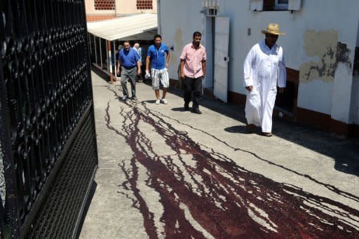 People pass by traces of pig's blood on the ground in front of the Montauban's mosque, southwestern France, after two pigs' heads were discovered hung at the gate of the entrance of the mosque