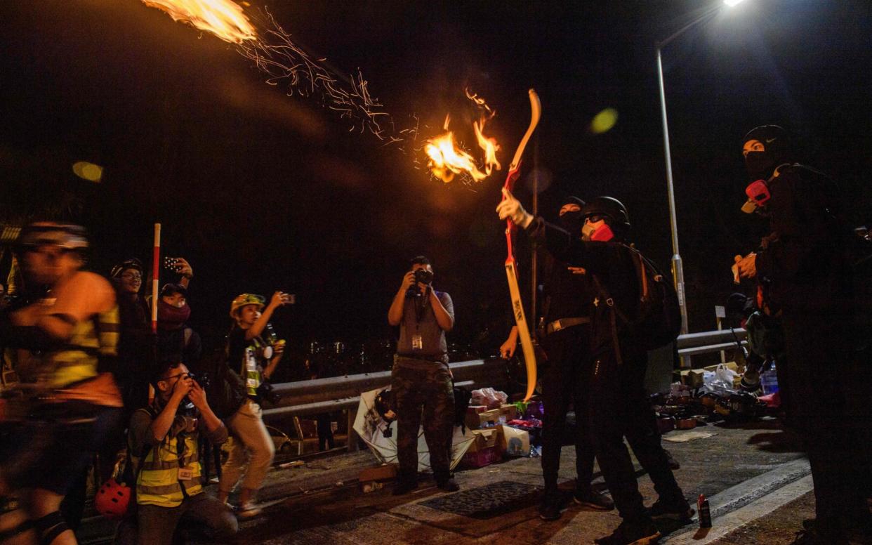 A protester releases a fire arrow with his bow to light a barricade at the Chinese University of Hong Kong - AFP