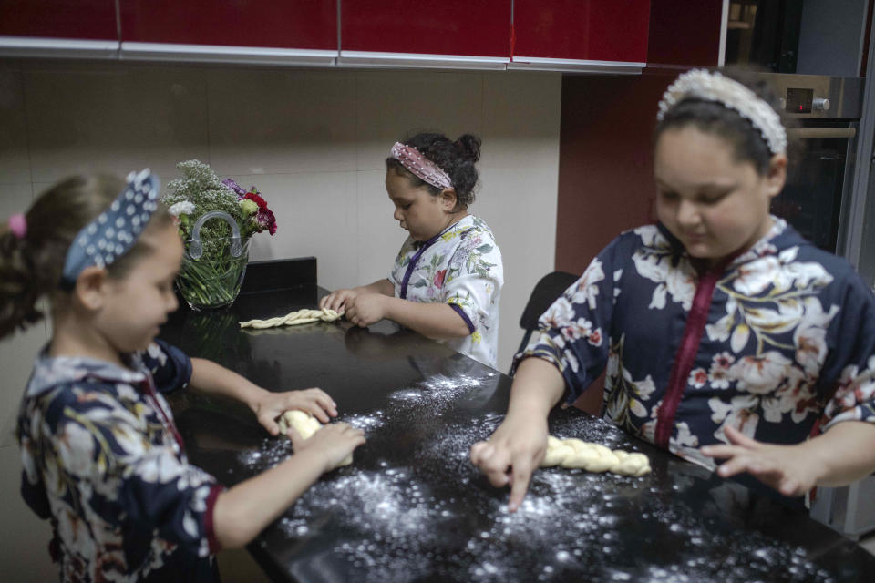 Musya Banon, right, and her sisters Nina, left, and Sara, center, bake challah bread for Shabbat, in their home in Casablanca, Morocco, Thursday, May 28, 2020. (AP Photo/Mosa'ab Elshamy)